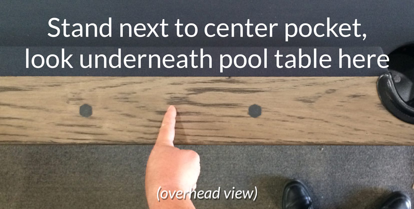 Finger pointing at pool table rail and slate